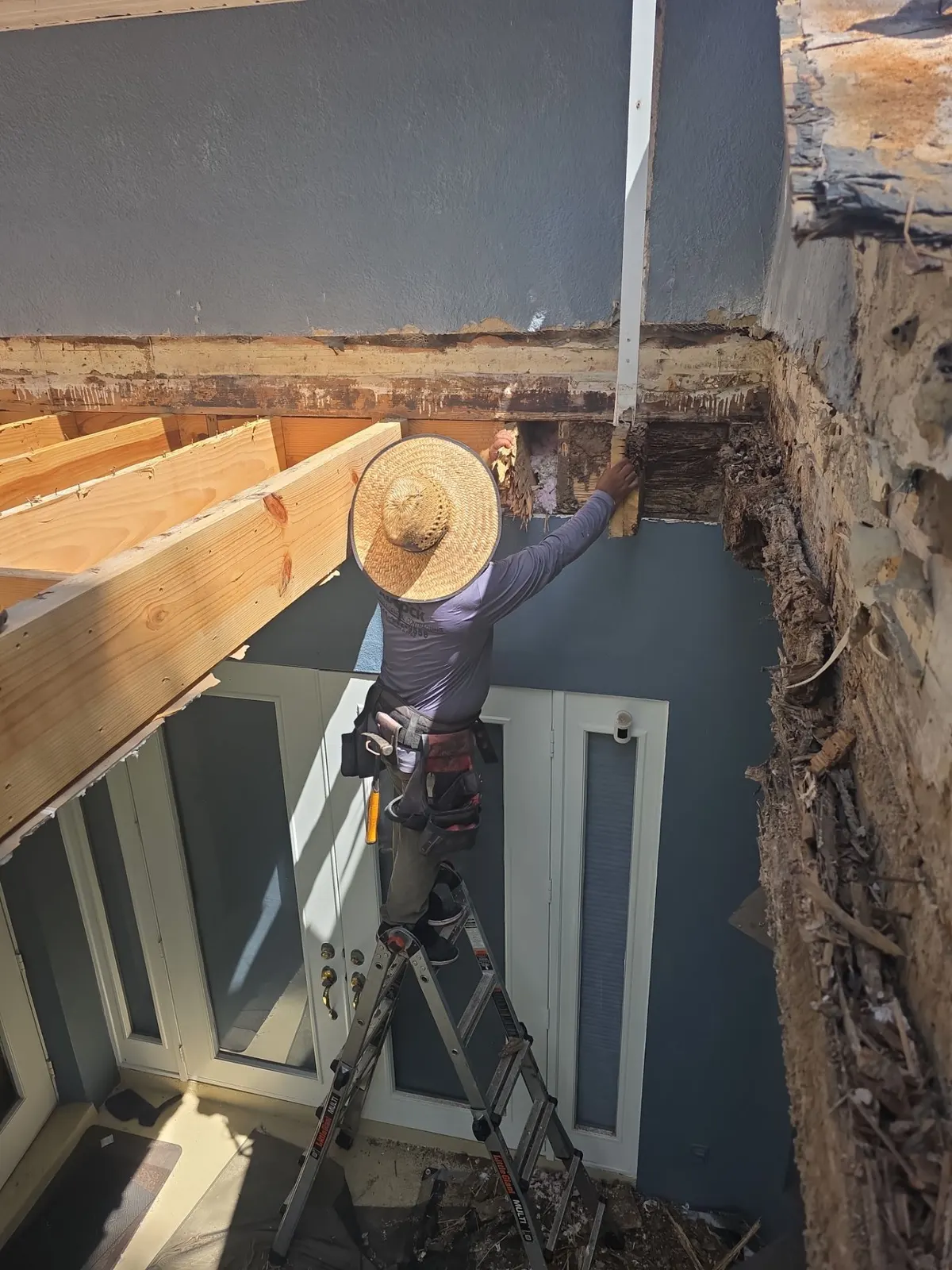 Carpenter replacing rotted framing over the lanai doors