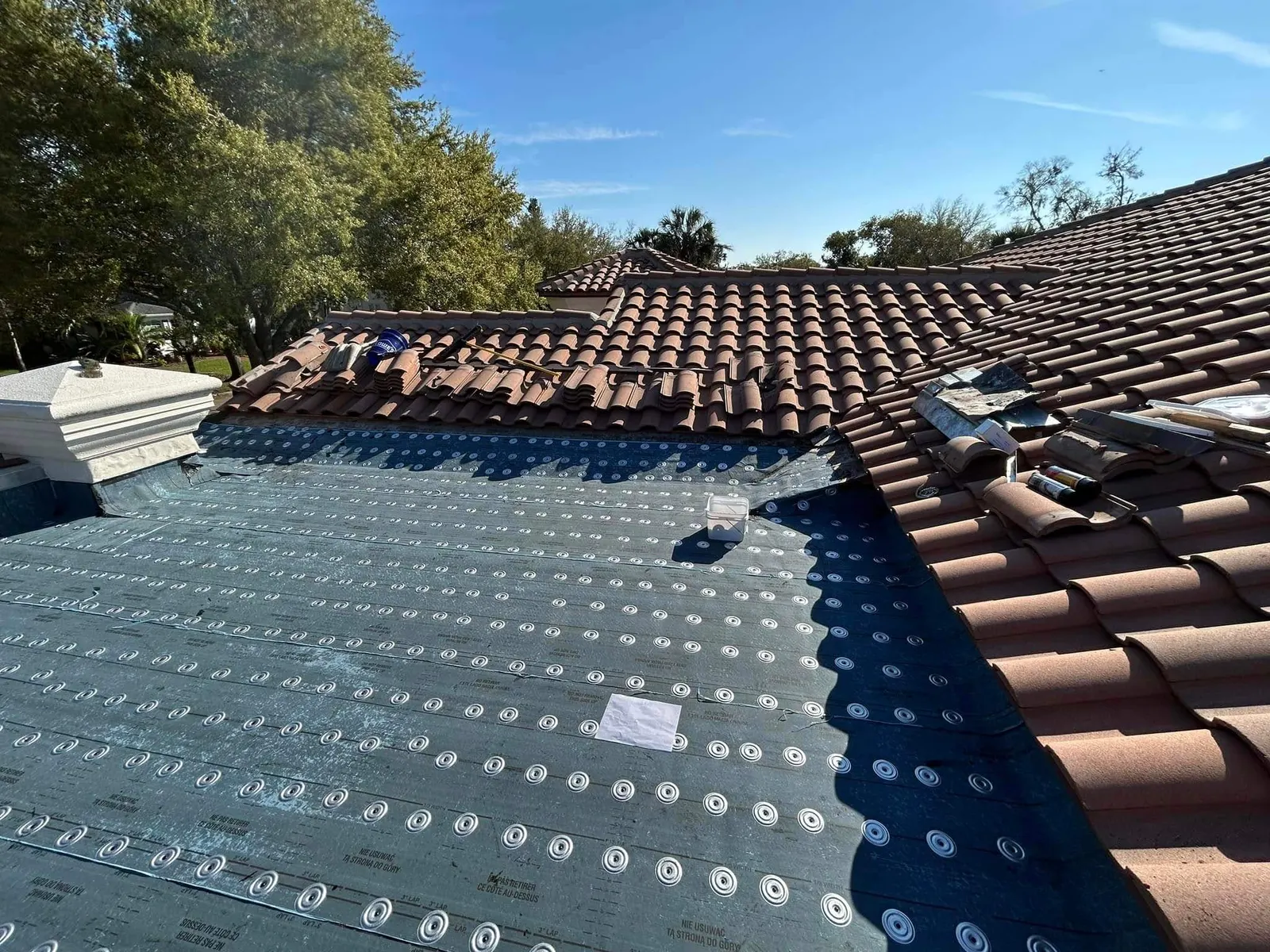 Underlayment going down beside barrel tile on the Winter Park roof