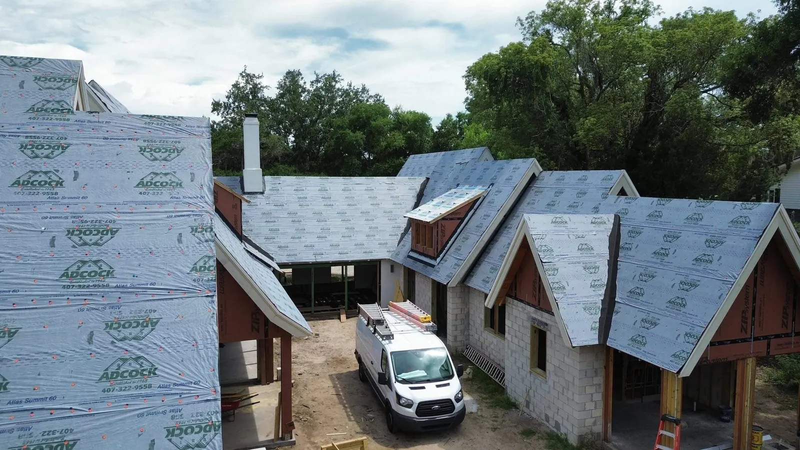 Adcock Roofing underlayment and dormers on the 16/12-pitch Winter Park roof, with the company van in the drive