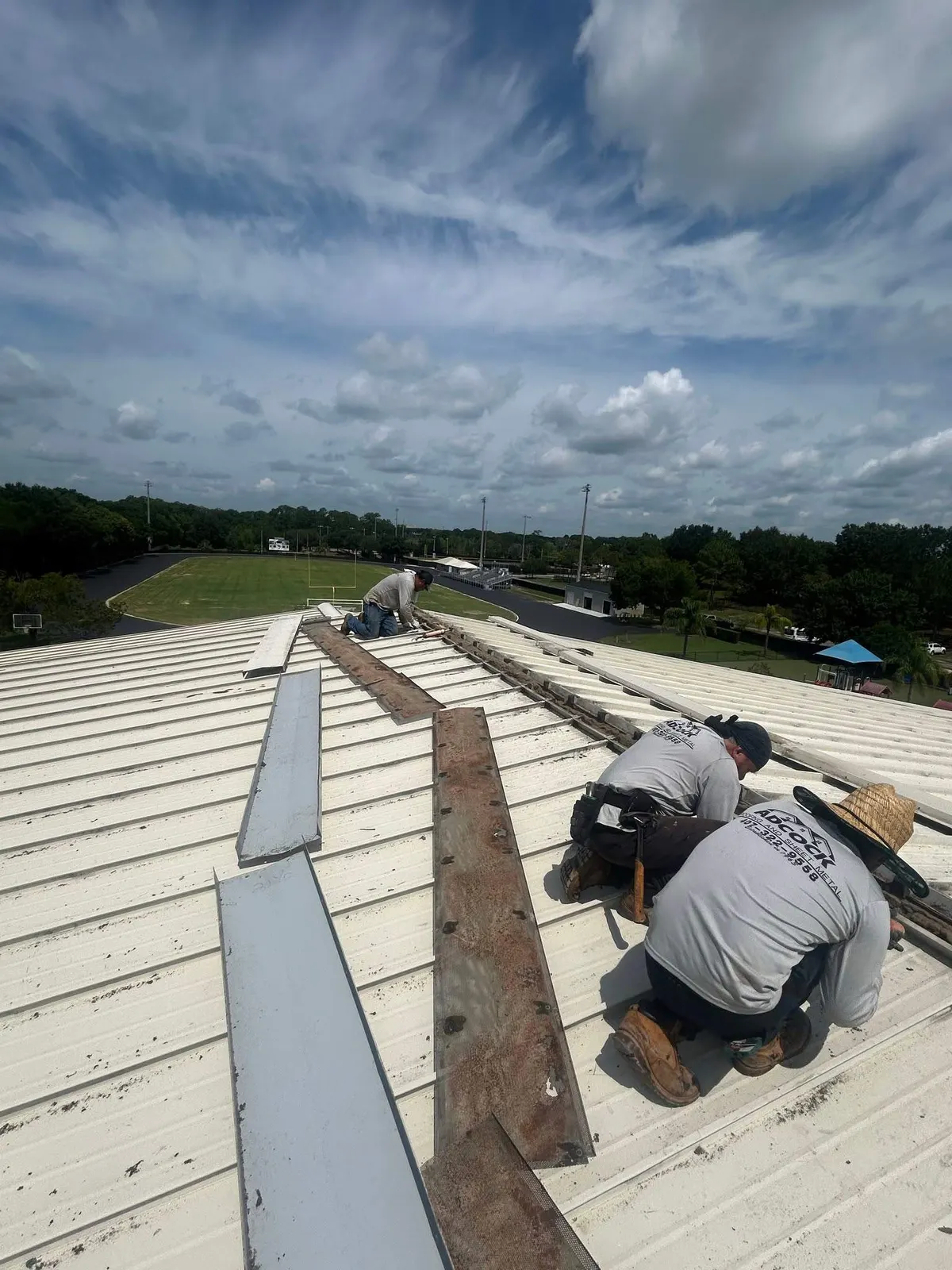 Crew repairing panels on a commercial metal building roof