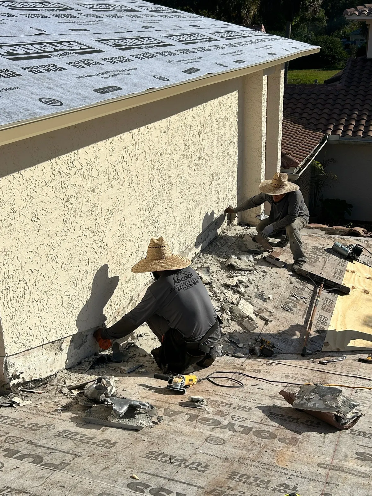 Crew removing stucco along the wall flashing on the Port Orange roof